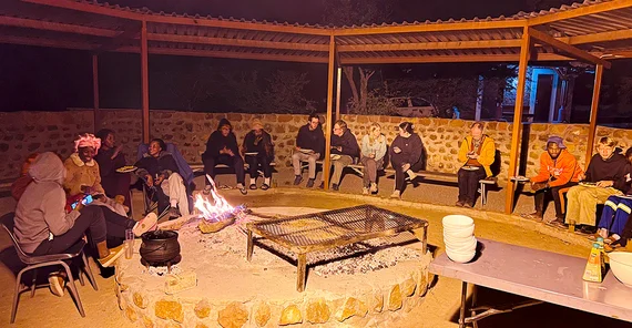 Menschen sitzen am Abend um ein Feuer