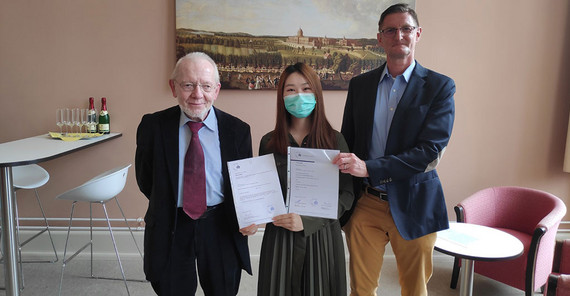 Die erste Absolventin im Master „Interkulturelle Wirtschaftskommunikation“ Xinyi Xu erhält von Studiengangsleiter Prof. Dr. Thomas Stehl (l.) und dem Dekan der Philosophischen Fakultät Prof. Dr. Hans-Georg Wolf ihre Abschlussurkunde. | Foto: Matthia Die erste Absolventin im Master „Interkulturelle Wirtschaftskommunikation“ Xinyi Xu erhält von Studiengangsleiter Prof. Dr. Thomas Stehl (l.) und dem Dekan der Philosophischen Fakultät Prof. Dr. Hans-Georg Wolf ihre Abschlussurkunde. | Foto: Matthias Zimmermann