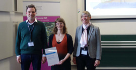 Foto von drei Personen, die bei einer Preisverleihung zusammenstehen