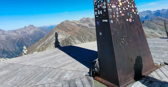 Eine hochalpine Berglandschaft mit Obelisk auf Gipfel.