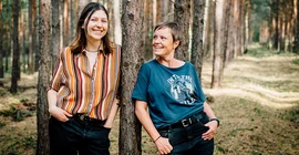 Mentoring-Team Sophie Kast (l.) und Nicole Körner (r.) an Kiefern im Wald gelehnt.