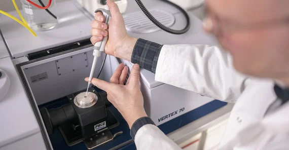 Mann bringt Flüssigkeit mit Pipette auf ein elektronisches Messgerät auf