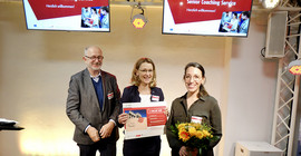 Das zweitplatzierte Team „Funster“ beim diesjährigen Senior Coaching Service Wettbewerb erhält das Preisgeld in Form eines symbolischen Schecks von Prof. Dr. Dieter Wagner. Foto: Tilo Bergemann.