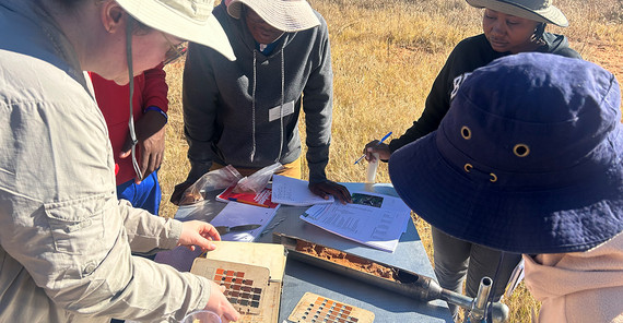 Forschende beugen sich über Geräte bei einer Übung im Gelände