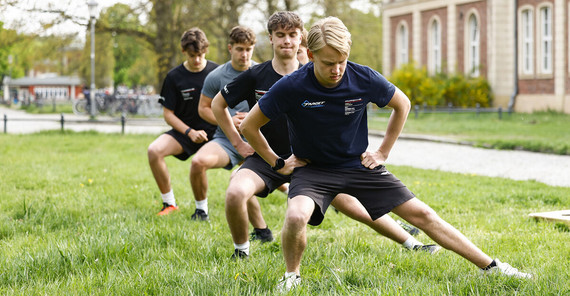 Die Rookies beim Dehnen Fünf junge Männer machen auf einer Wiese Dehnungsübungen.