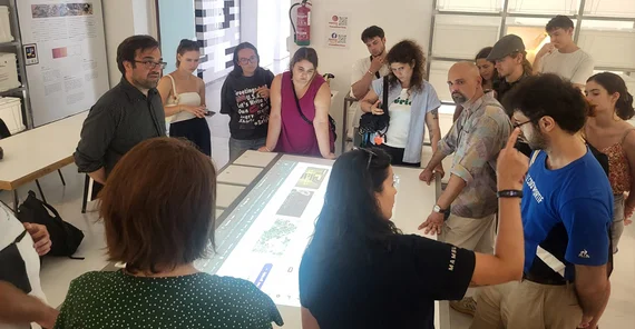 Teilnehmende der Exkursion stehen um einen Lichttisch herum. Eine Frau erklärt.