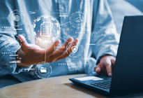 Eine Hand mit visualisierten Daten vor einem Laptop