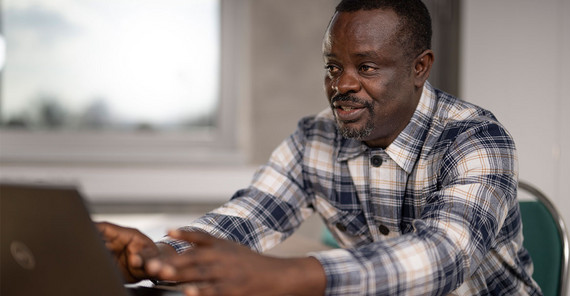 Der botsuanische Bodenwissenschaftler Prof. Peter Eze Der botsuanische Bodenwissenschaftler Prof. Peter Eze sitzt am Schreibtisch an seinem Laptop.