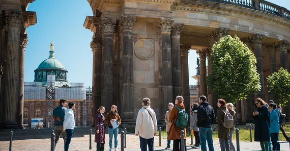 Gruppe von Menschen steht bei der Kolonnade des Neuen Palais