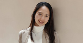 Das ist ein Porträtfoto. Es zeigt eine Frau vor einem hellbraunen Hintergrund.