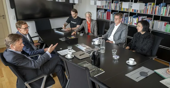 Mehrere Menschen sitzen in einem Besprechungsraum um einen Tisch