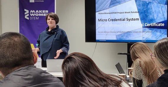 Eine Person referiert vor digitaler Anzeige.