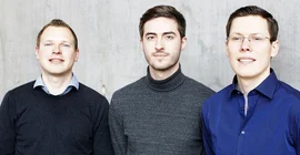 Portrait von drei Männern vor einer Wand