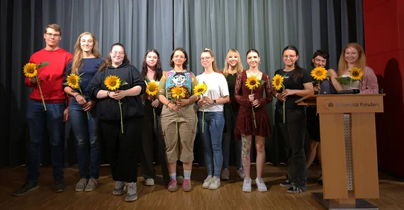 Gruppenfoto der ausgelernten Auszubildenden. Alle halten je eine Sonnenblume in den Händen.