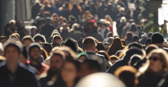 View of a crowd of people on a sidewalk. No faces are clearly visible.