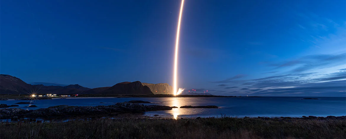Illuminierter Raketenstart aus der Ferne am Nachthimmel. - 
