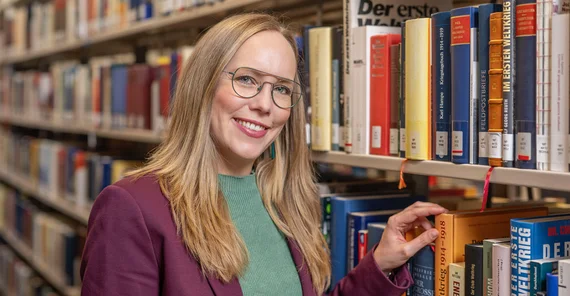 Frau steht an einem Bücherregal