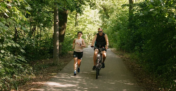 Lena Sonntag mit ihrem Trainer am Templiner See. Sie geht, er fährt daneben Rad.