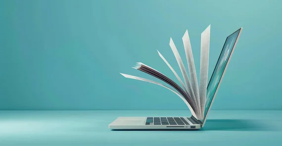 Ein aufgeklappter Laptop von der Seite, aus denen Buchseiten hinaus ragen.