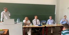 Gruppe von Männern im Gespräch in einem Uni-Hörsaal
