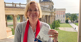 Foto einer Frau an einem Fenster mit einem Buch in der Hand