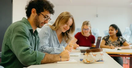 Vier junge Menschen sitzen an einem Tisch und sprechen
