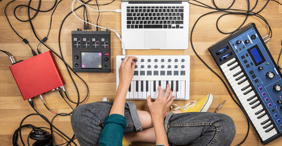 „Das beste Mittel, die Ohren offen zu halten, ist das Musizieren – mit einem Instrument oder der eigenen Stimme“, sagt Isolde Malmberg. | Foto: AdobeStock/Photoboyko Person sitzt auf dem Fußboden im Schneidersitzt, umgeben von Keyboard, Laptop, Soundboard und anderen Geräten zum musizieren. Das Foto ist von AdobeStock/Photoboyko.