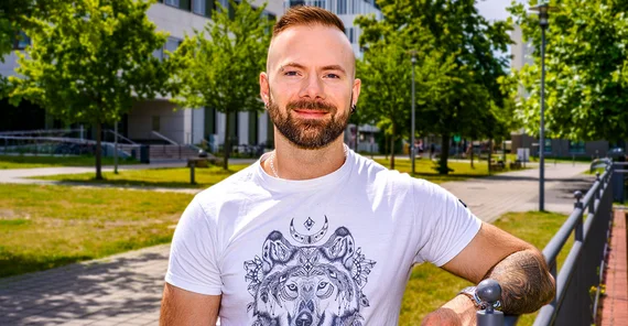 Kognitionswissenschaftler Alex Miklashevsky im Portrait. Leger im Shirt an ein Geländer gelehnt.