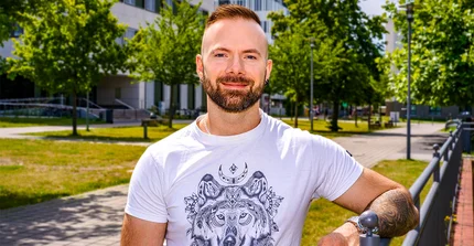 Kognitionswissenschaftler Alex Miklashevsky im Portrait. Leger im Shirt an ein Geländer gelehnt.