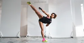 Marie Mouroum bei sportlicher Aktivität - das rechte Bein ist in einem High-Kick über die Höhe ihres Kopfes erhoben.