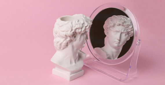 Narzisstische Menschen schwanken sehr stark zwischen Höhenflügen und großer Empfindlichkeit. Bust of David admiring himself in a mirror on a pink background. Symbolic representation of narcissism.