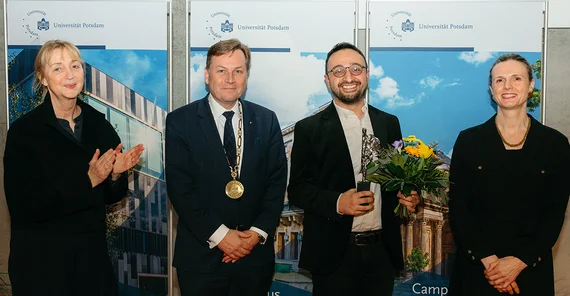 Vier Menschen stehen bei einer Preisverleihung zusammen