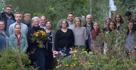Fast 20 Vertretende verschiedener Einrichtungen Brandenburgs posieren für ein Gruppenbild im Campusgarten der FH Potsdam.