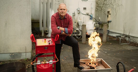 Ulf Lepszy posiert neben Flamme und Feuerlöscher.
