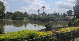 Taman-Ayun-Tempel, malerische Szenerie am Wasser, Palmen und blauer Himmel