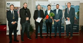 Sechs Personen stehen in einem Hörsaal bei einer Preisverleihung nebeneinander