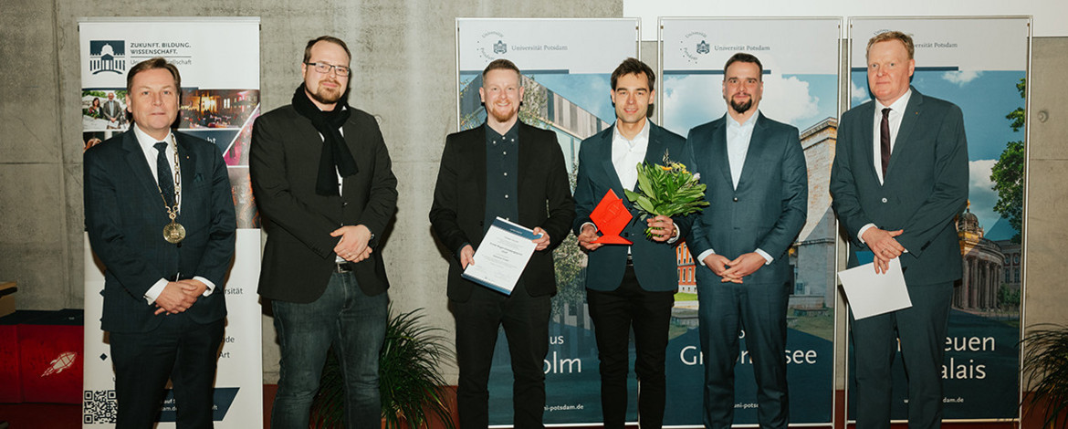 Sechs Personen stehen in einem Hörsaal bei einer Preisverleihung nebeneinander - 