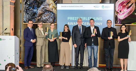 Gruppenfoto von sieben Menschen auf einer Bühne