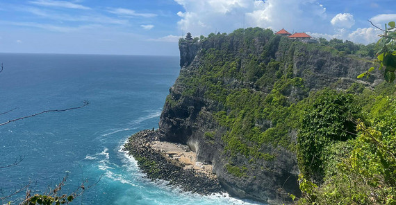 Hinduistischer Tempel in Uluwatu an den Klippen der Halbinsel. Die Klippen sind stark bewachsen und befinden sich direkt am Meer.