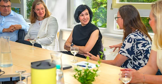 Mehrere Menschen sitzen in einem Besprechungsraum um einen Tisch