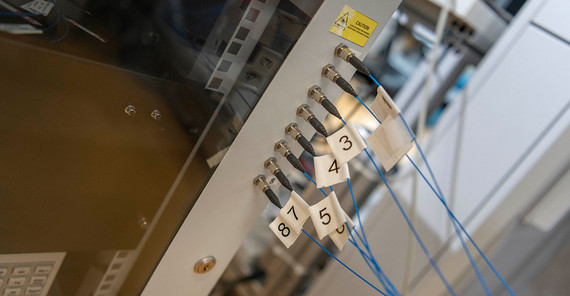 Sebastian Zimmermann schließt die Glasfaserkabel der im Reaktor befindlichen Messsonde für die Photonendichtewellen-Spektroskopie an das Spektrometer an.