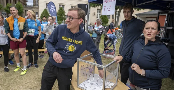 Ein Mann greift in eine Losbox und zieht ein Los