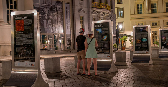 Ausstellung auf dem Potsdamer Alten Markt Zwei Personen sehen sich die Ausstellung auf dem Potsdamer Alten Markt bei Nacht an.
