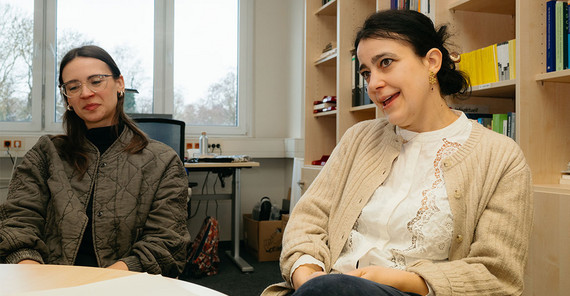 Zwei Personen sitzen an einem runden Tisch und werden interviewt.