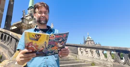 Sander Lass auf den Stufen des Haus 9 am Neuen Palais. Er liest ein Mosaik-Heft.