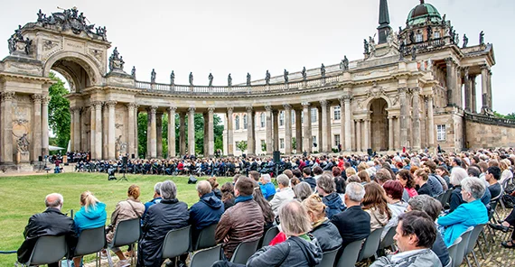 Gäste sitzen vor den Kolonnaden und verfolgen das Programm