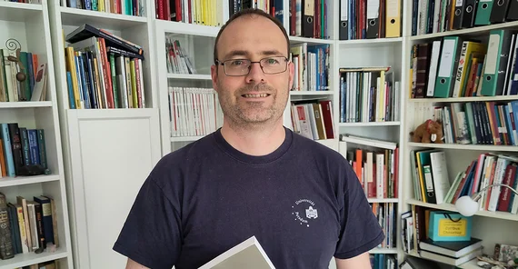 Portrait von Měto-Nowak vor Bücherwand