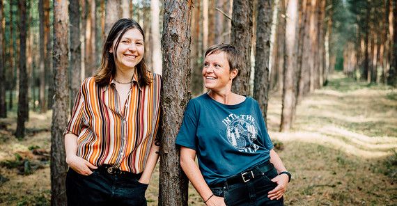 zwei Frauen lehnen an einem Baum