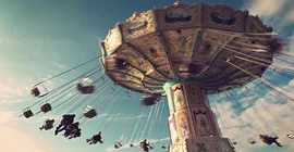 Bild: Adobe Stock/ Tom Bayer. Auf dem Bild ist ein fahrendes Kettenkarussel abgebildet.